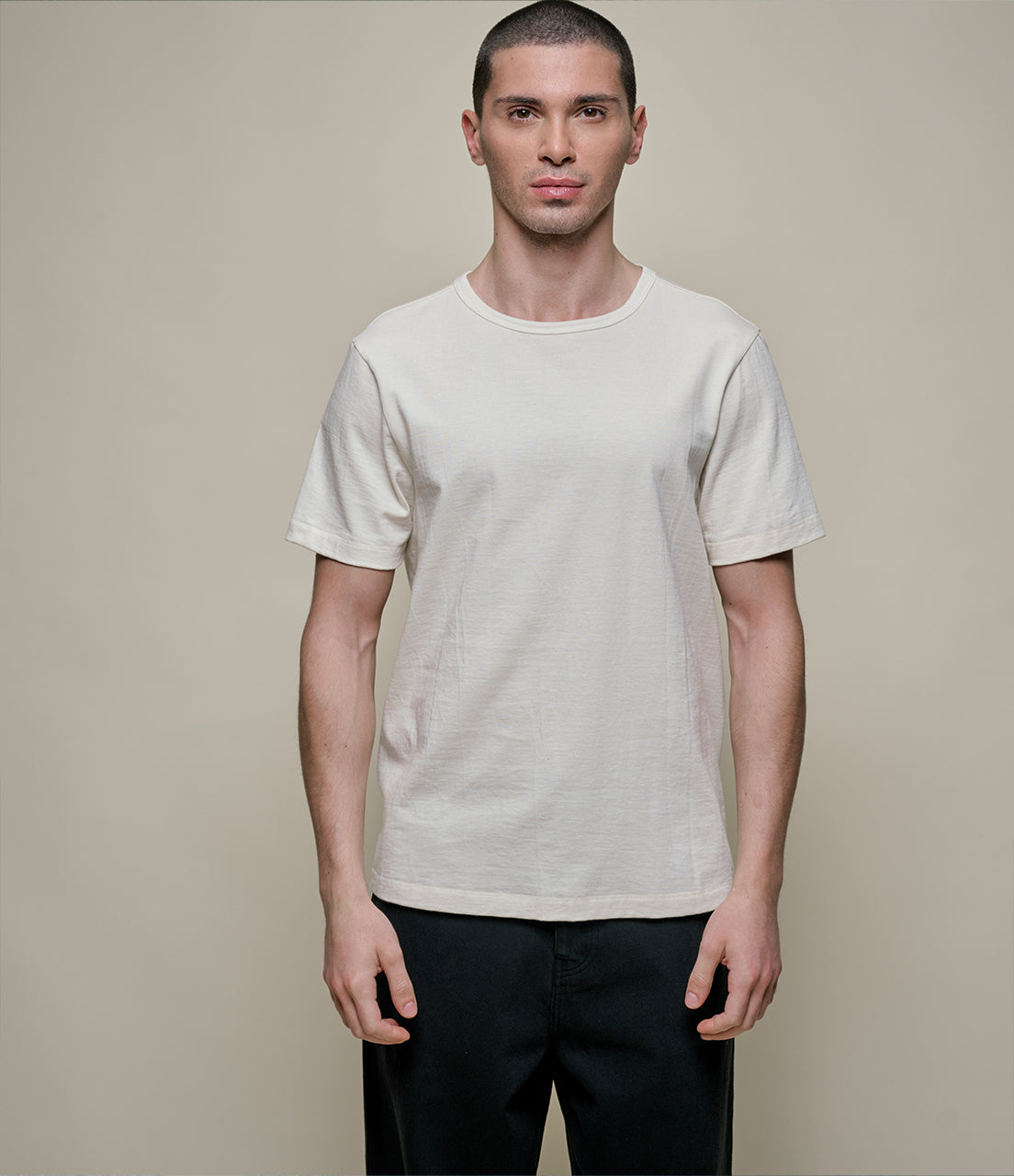 Man wearing a beige t-shirt against a beige background