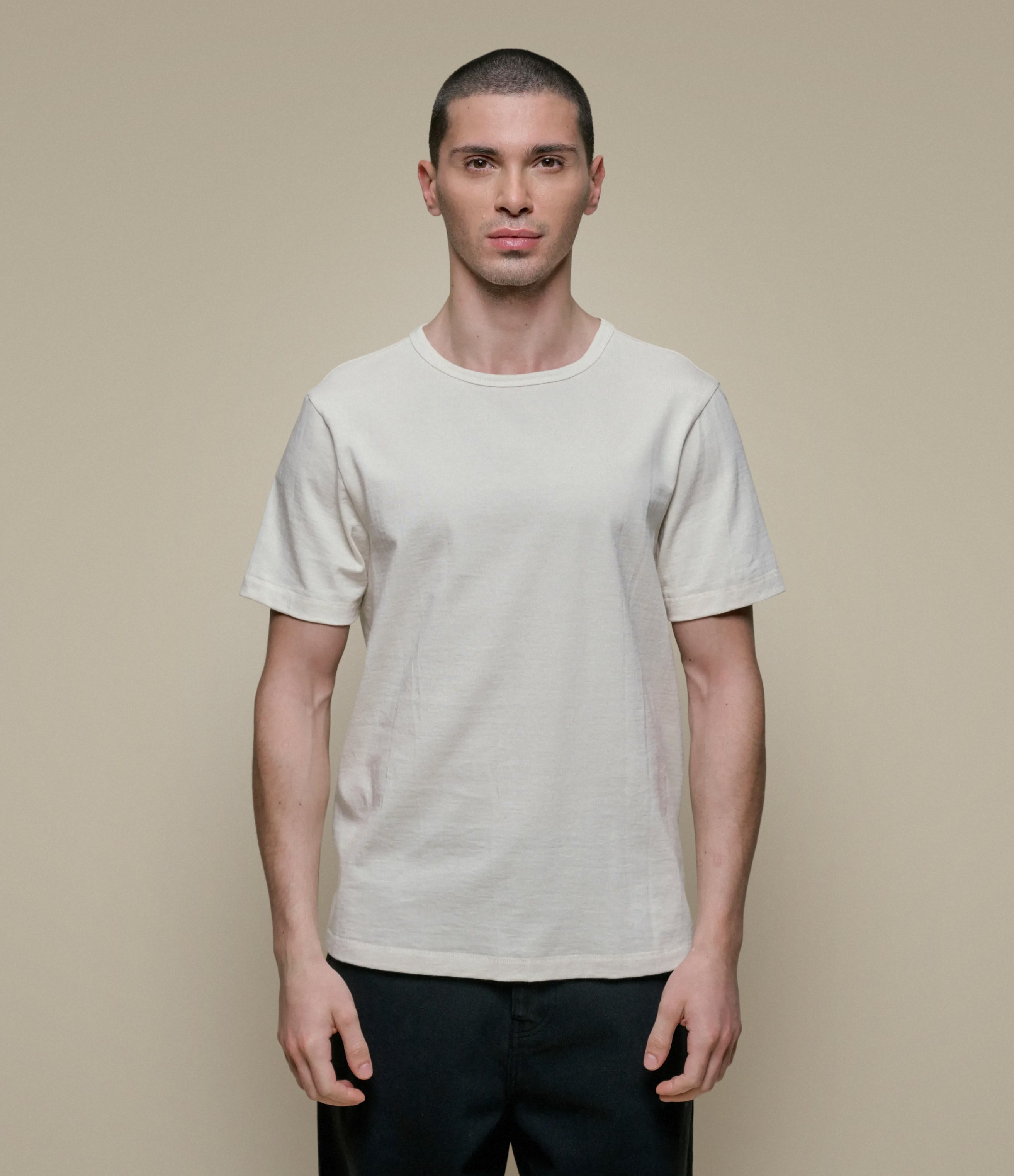 Man wearing a beige t-shirt against a beige background