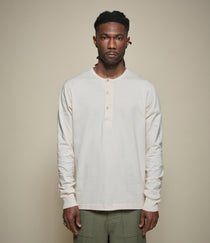 Man wearing a beige long-sleeve henley shirt against a plain background