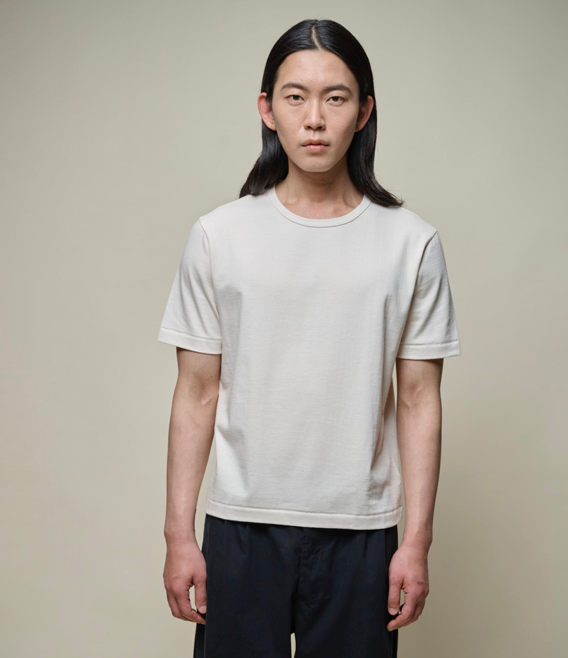 man wearing a nature, short-sleeved, cropped fit T-shirt with a round neckline.