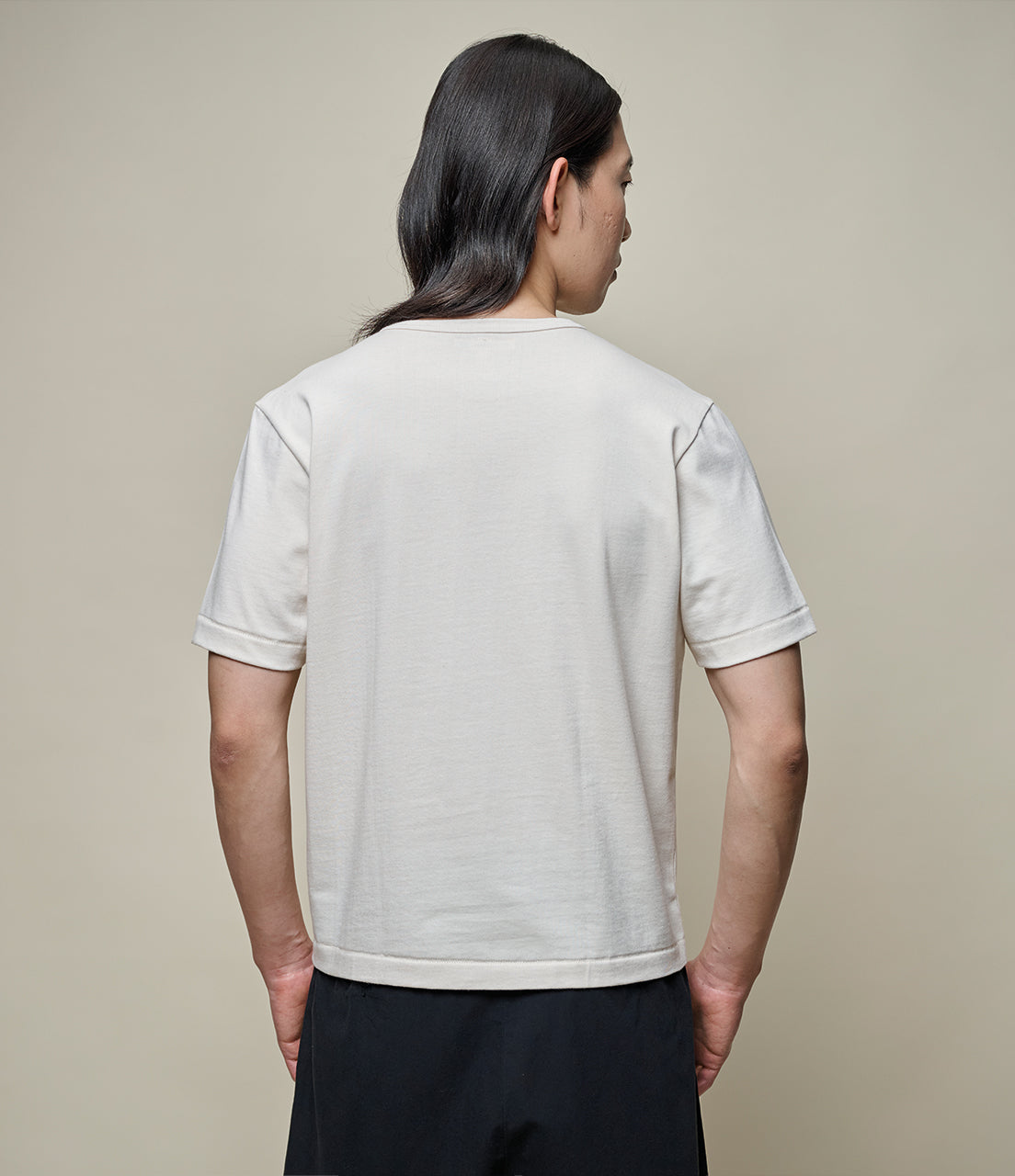 Person wearing a beige t-shirt against a beige background
