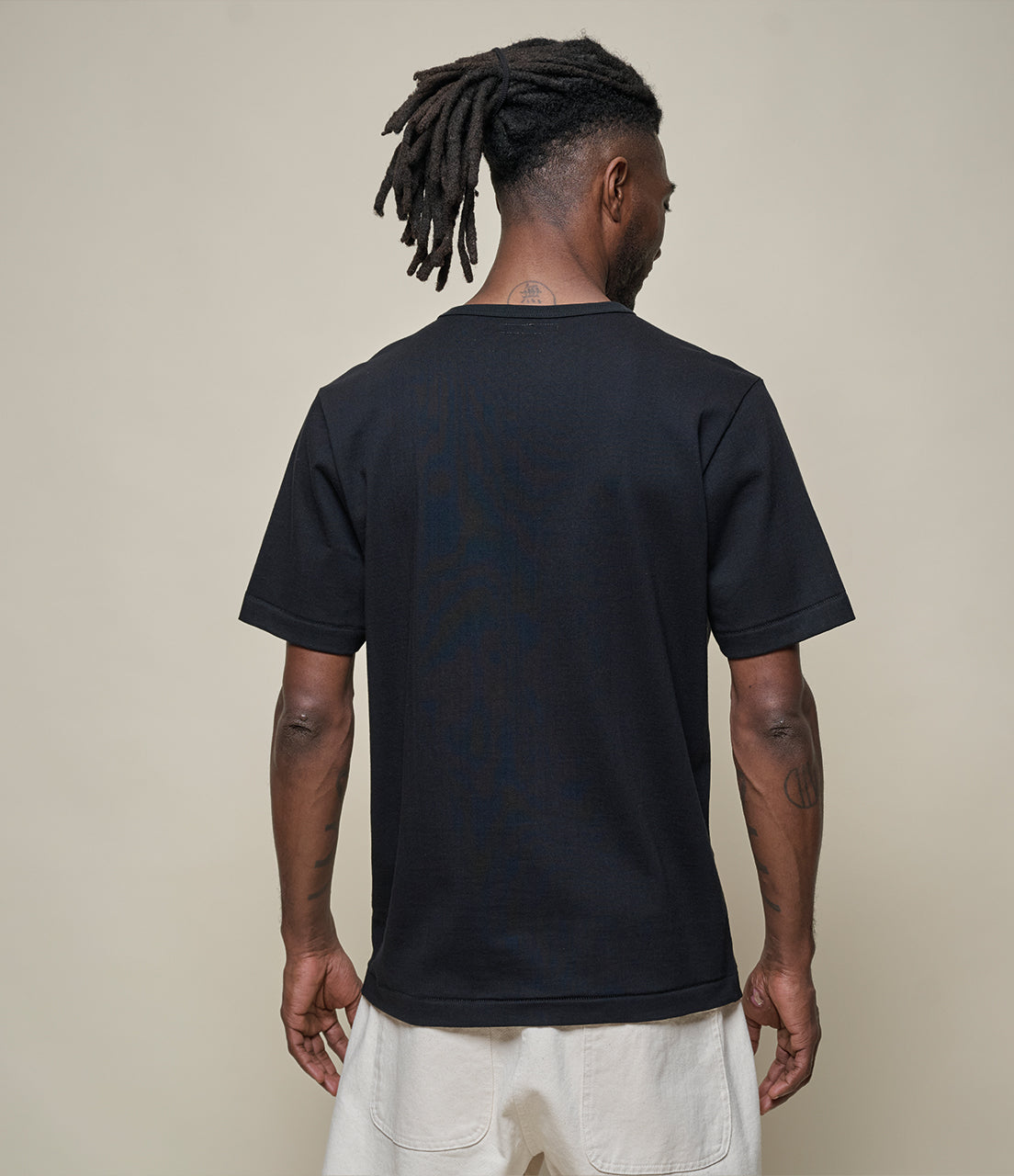 Person wearing a black t-shirt with a plain background