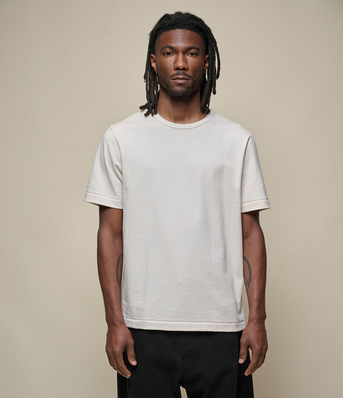 Man wearing a plain white t-shirt against a beige background