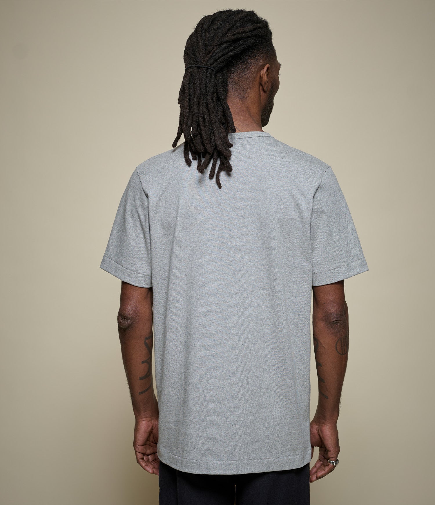 Person wearing a gray t-shirt against a beige background