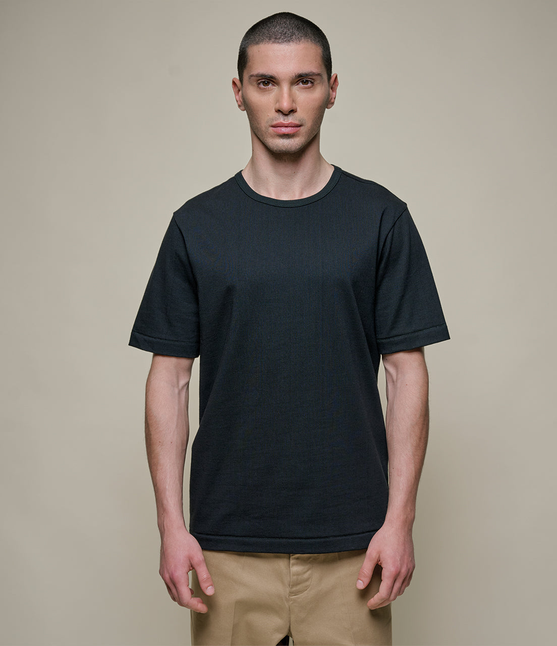 Man wearing a black t-shirt against a beige background