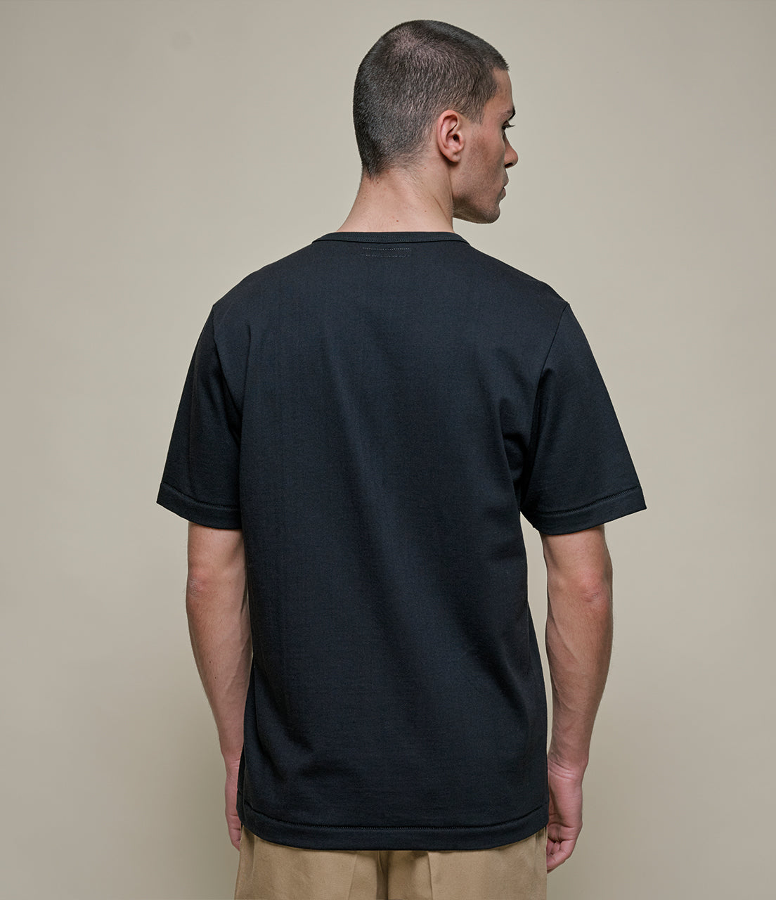 Man wearing a black t-shirt against a beige background
