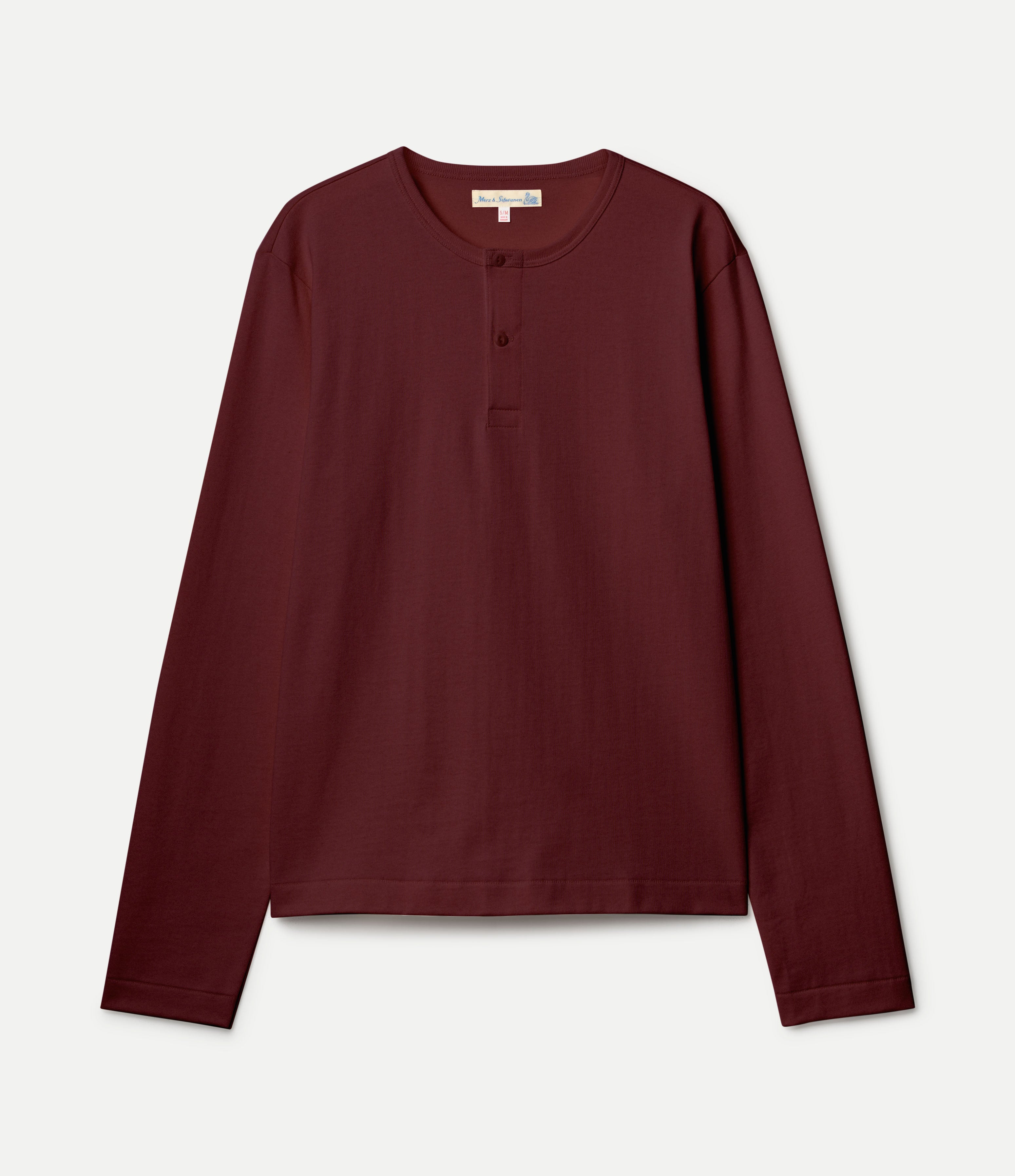 A cropped long-sleeve henley shirt in deep burgundy, laid flat against a light off-white background.