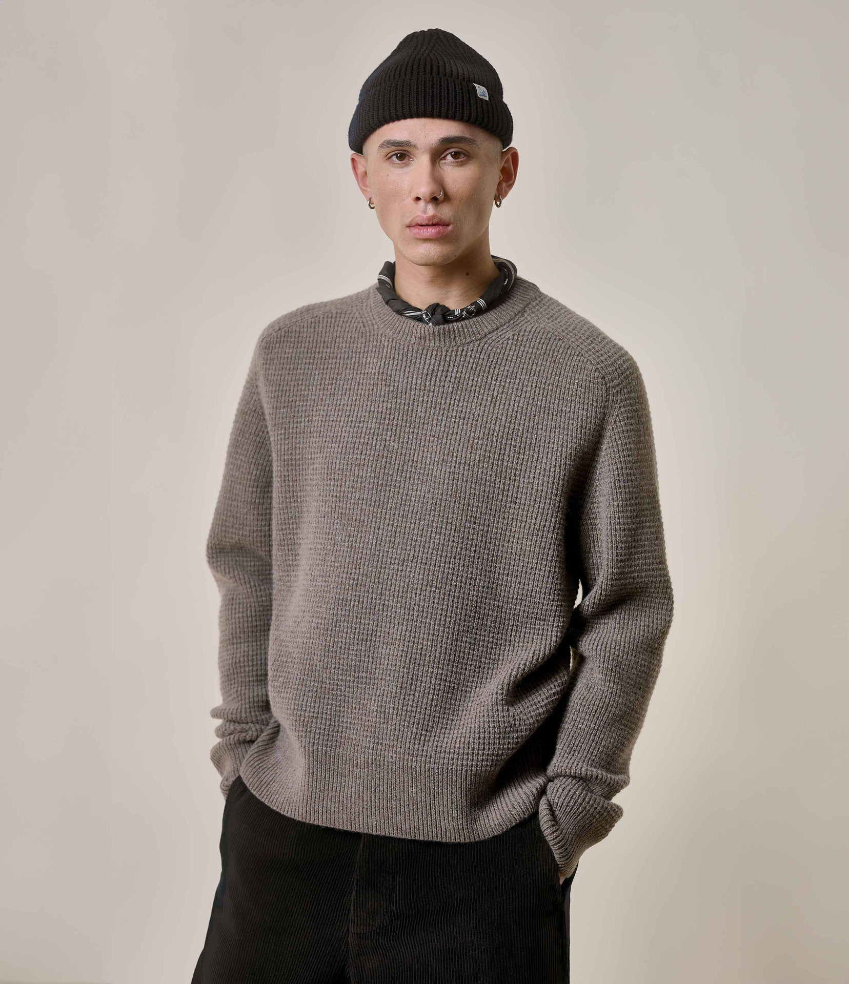 Person wearing a gray sweater and black beanie against a plain background