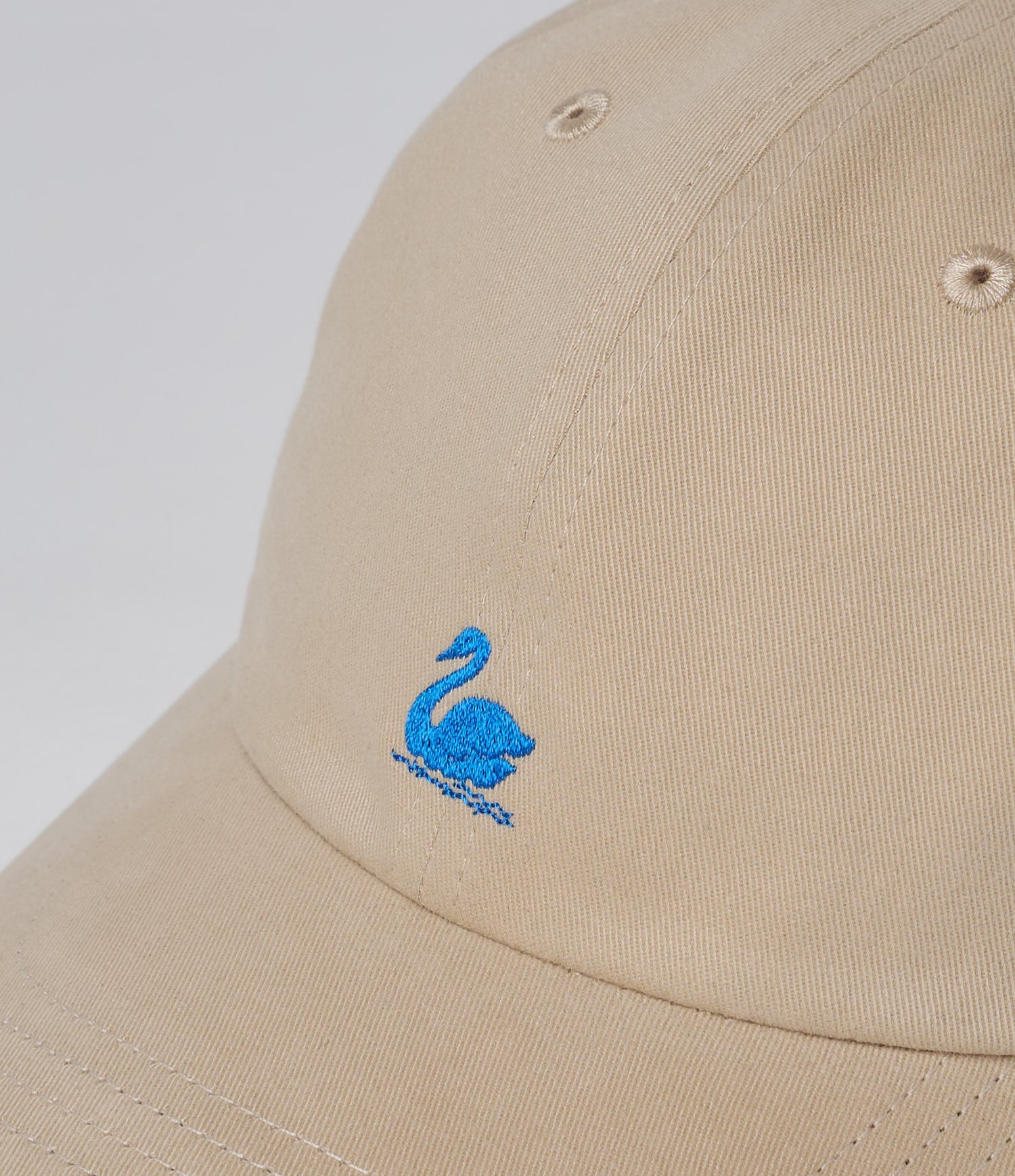 Beige cap with a blue embroidered swan design on a white background