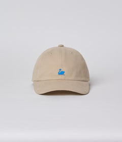 A beige cotton twill cap with a small embroidered swan logo in blue on the front panel.