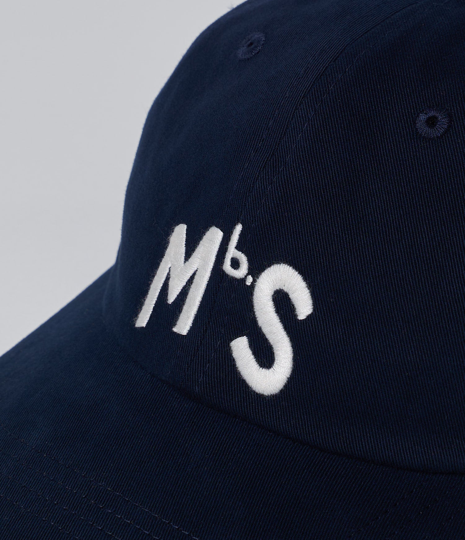 Navy blue cap with 'Mbs' logo on a light gray background
