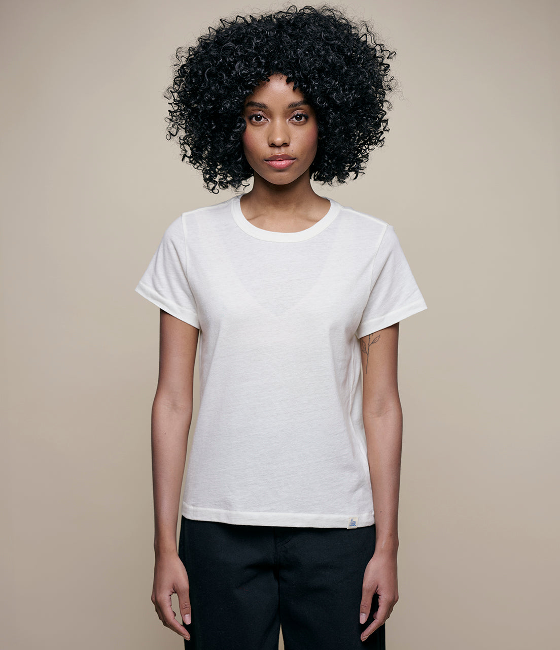 Woman wearing a white cashmere t-shirt against a beige background