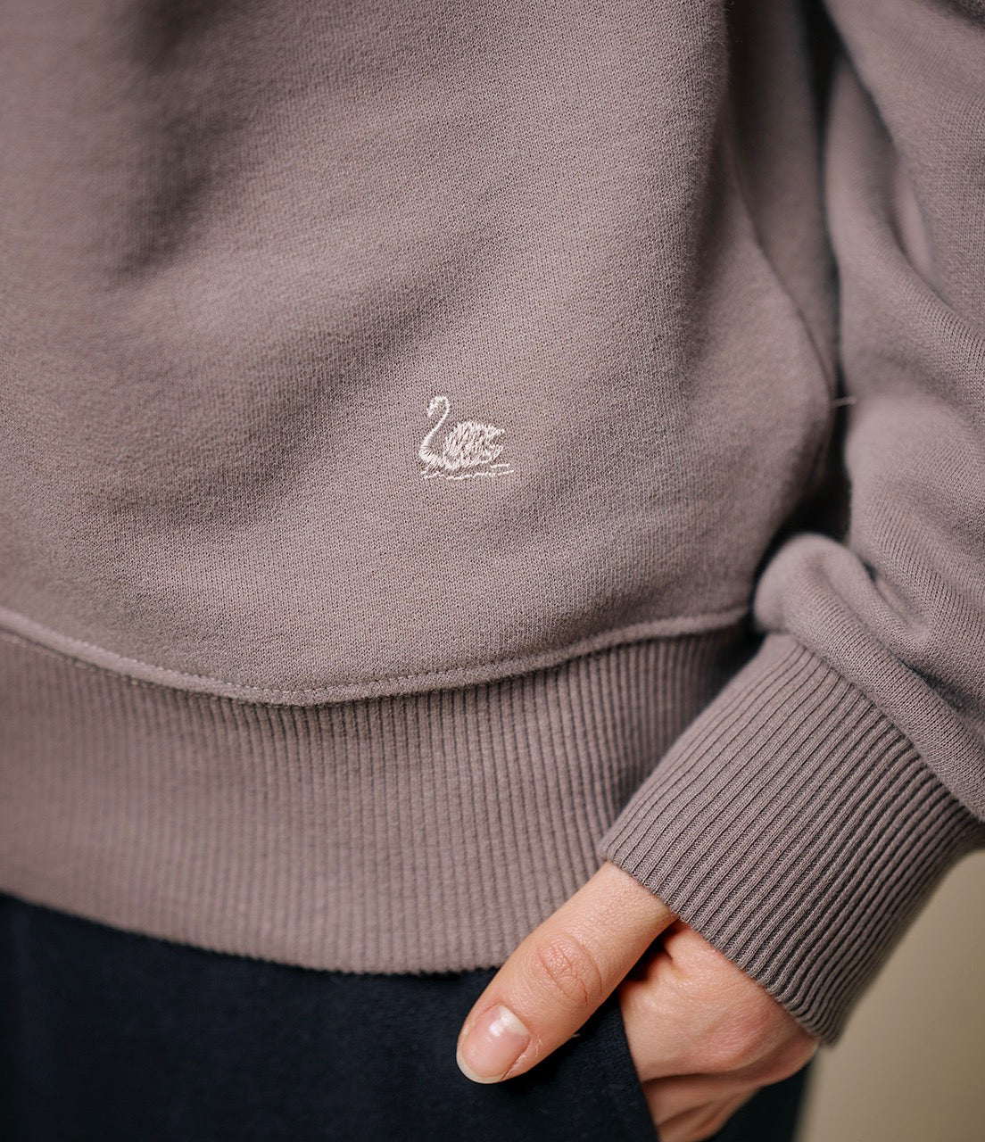 Close-up of a gray sweater with a small logo on the chest.