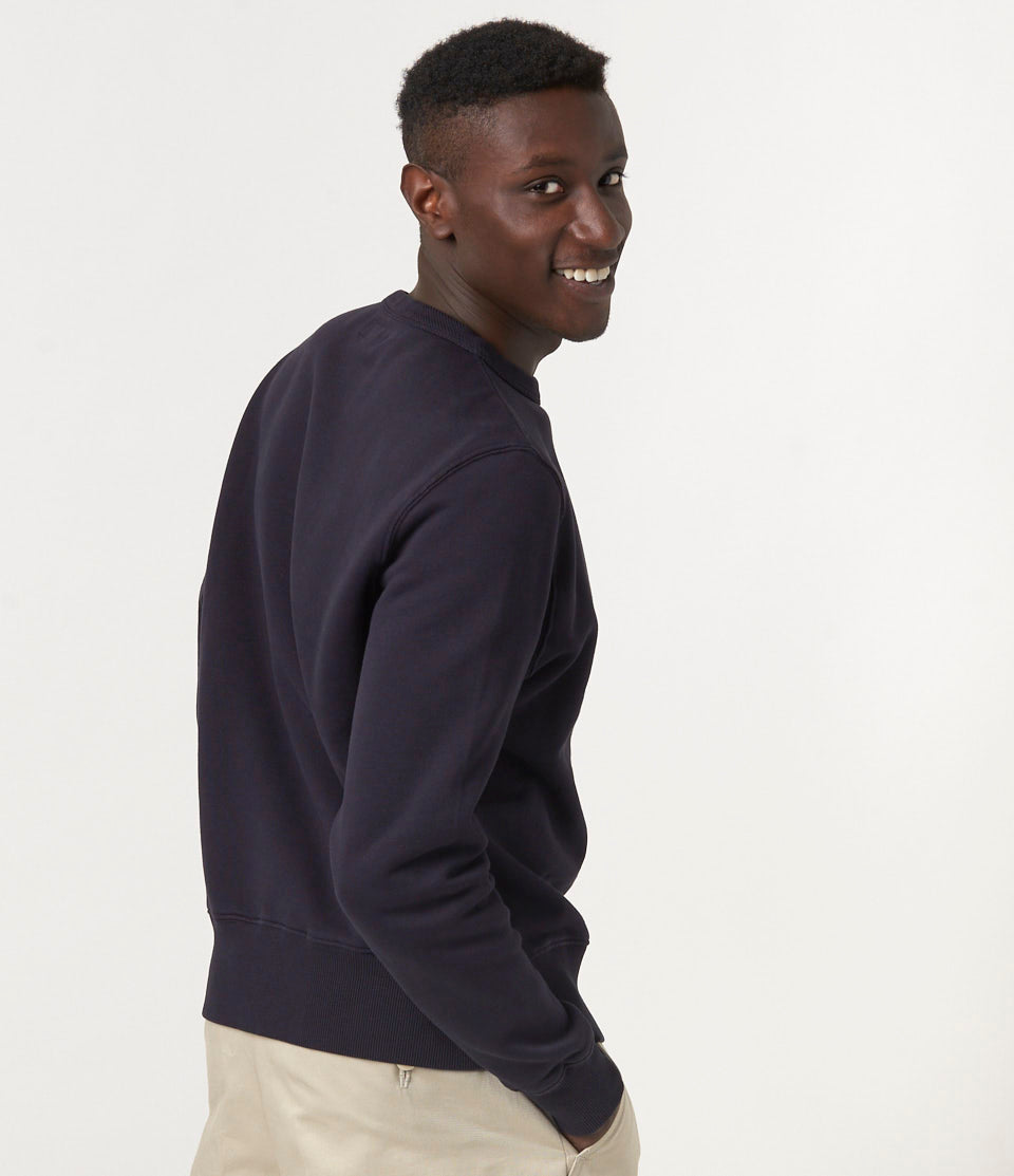Person wearing a dark grey sweater against a plain background