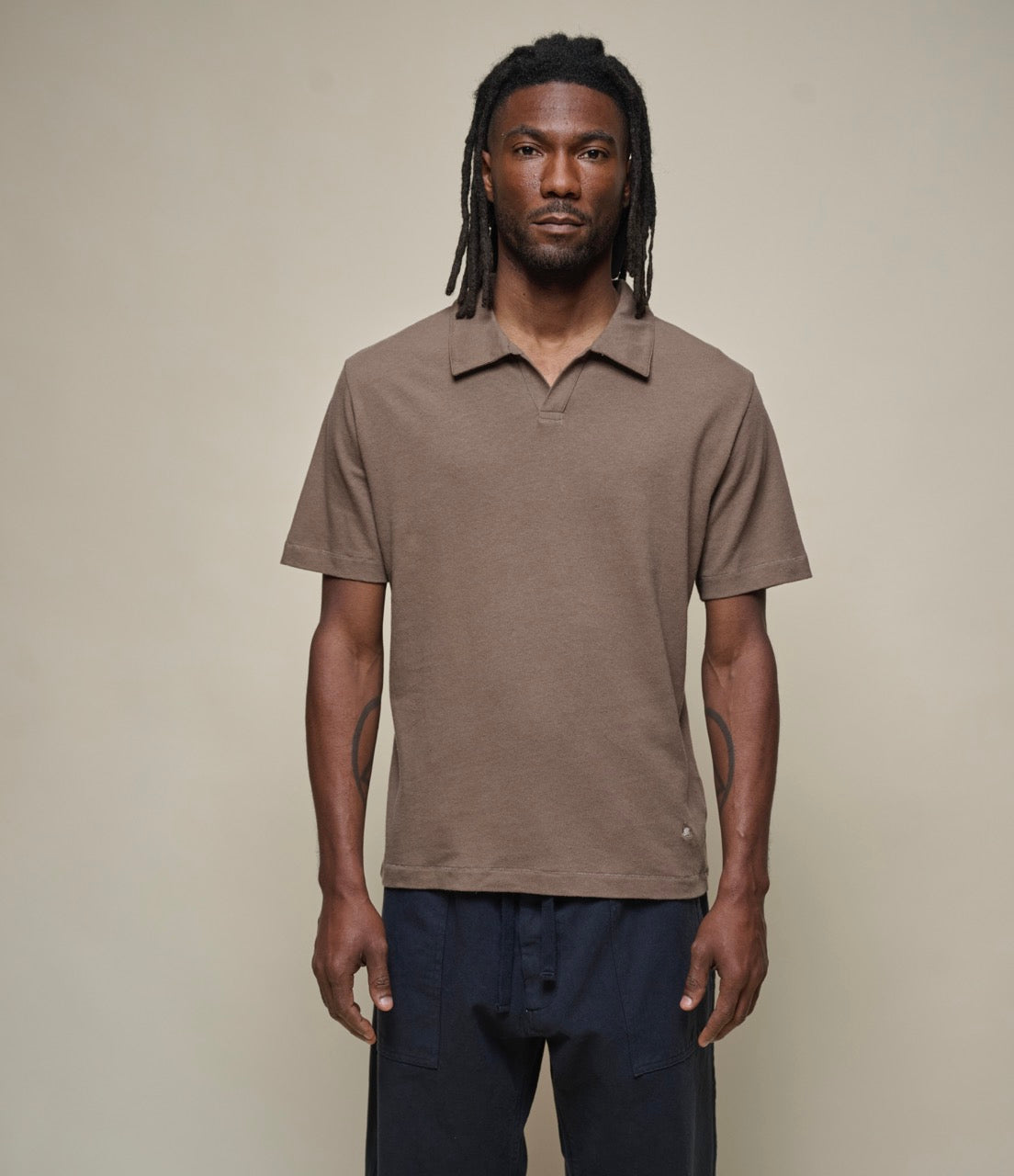 A person wearing a brown, short-sleeved  linen polo shirt