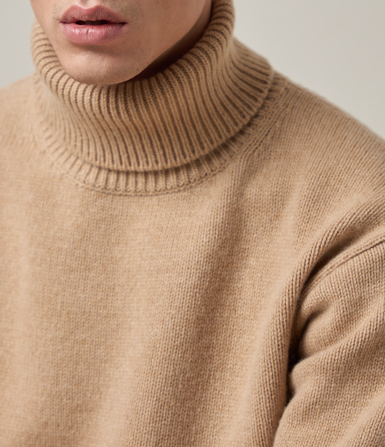 Close-up of a person wearing a beige turtleneck sweater.