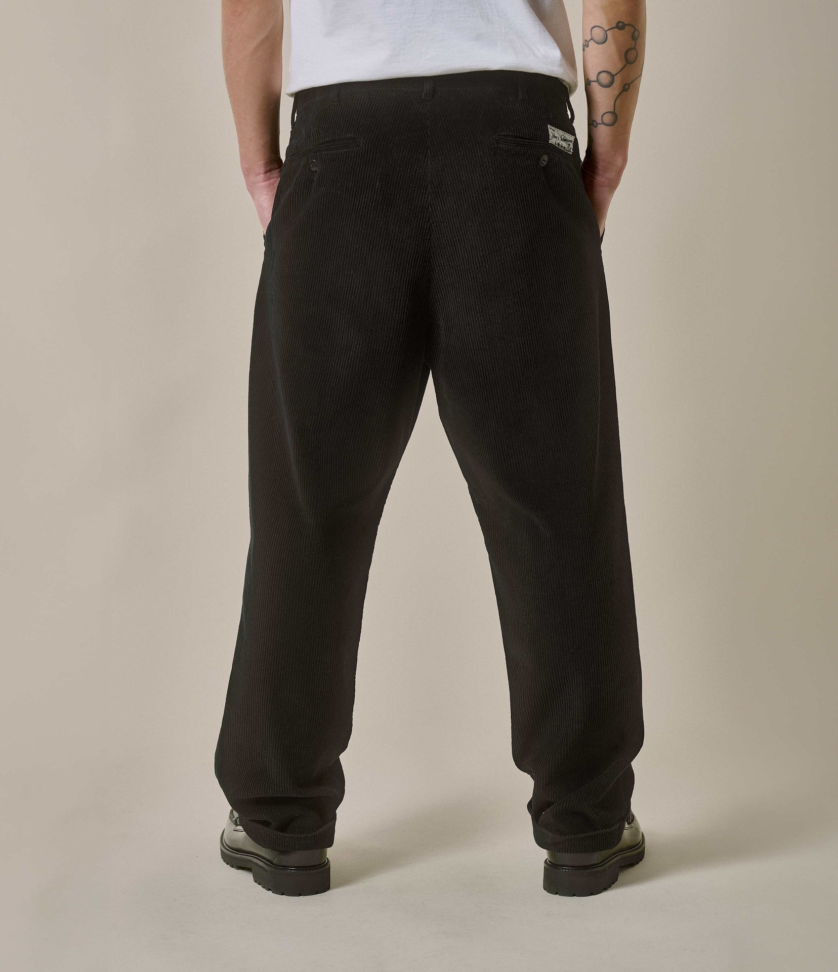Person wearing black pants against a plain background