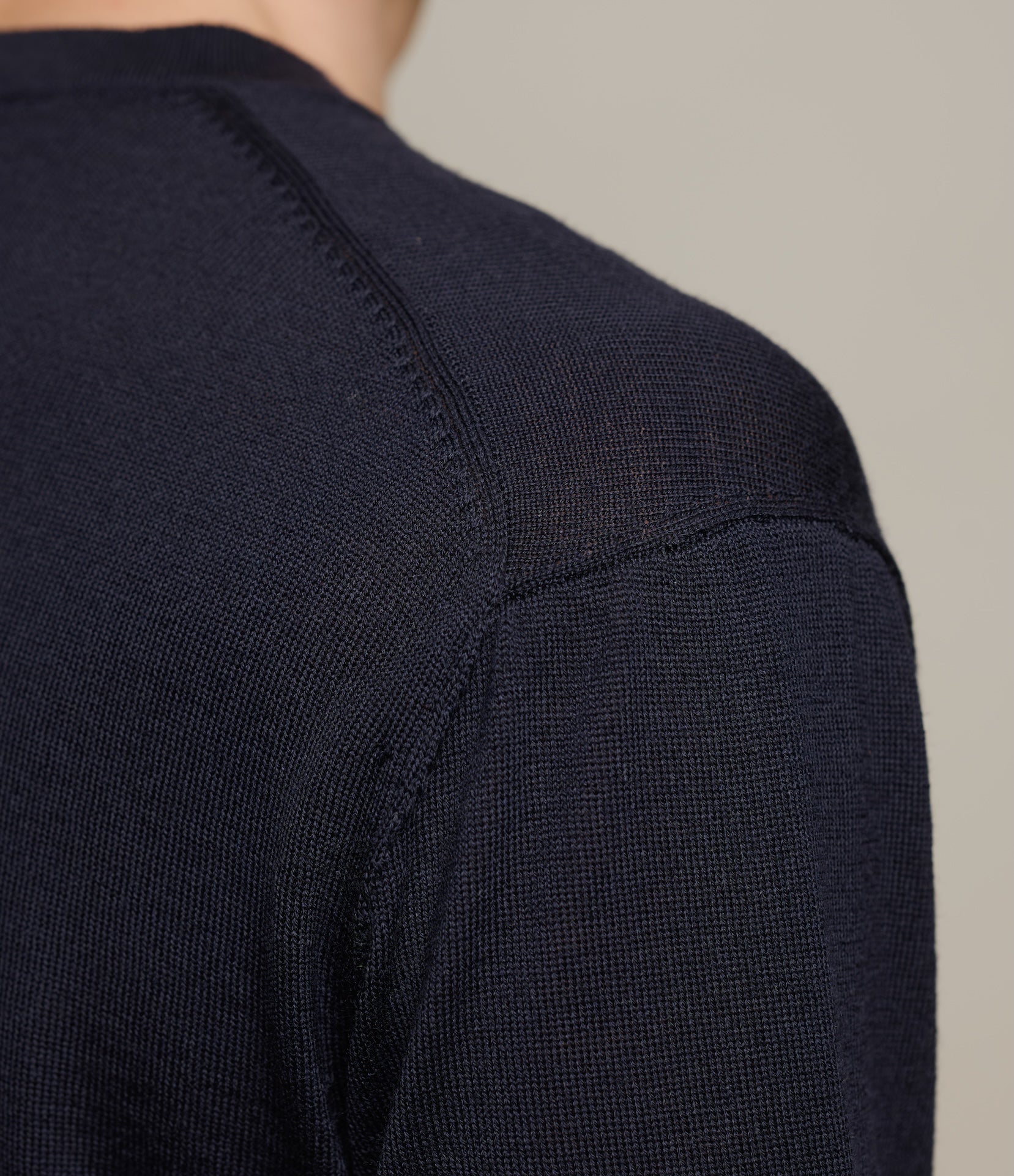 Close-up of a dark blue merino wool garment on a neutral background