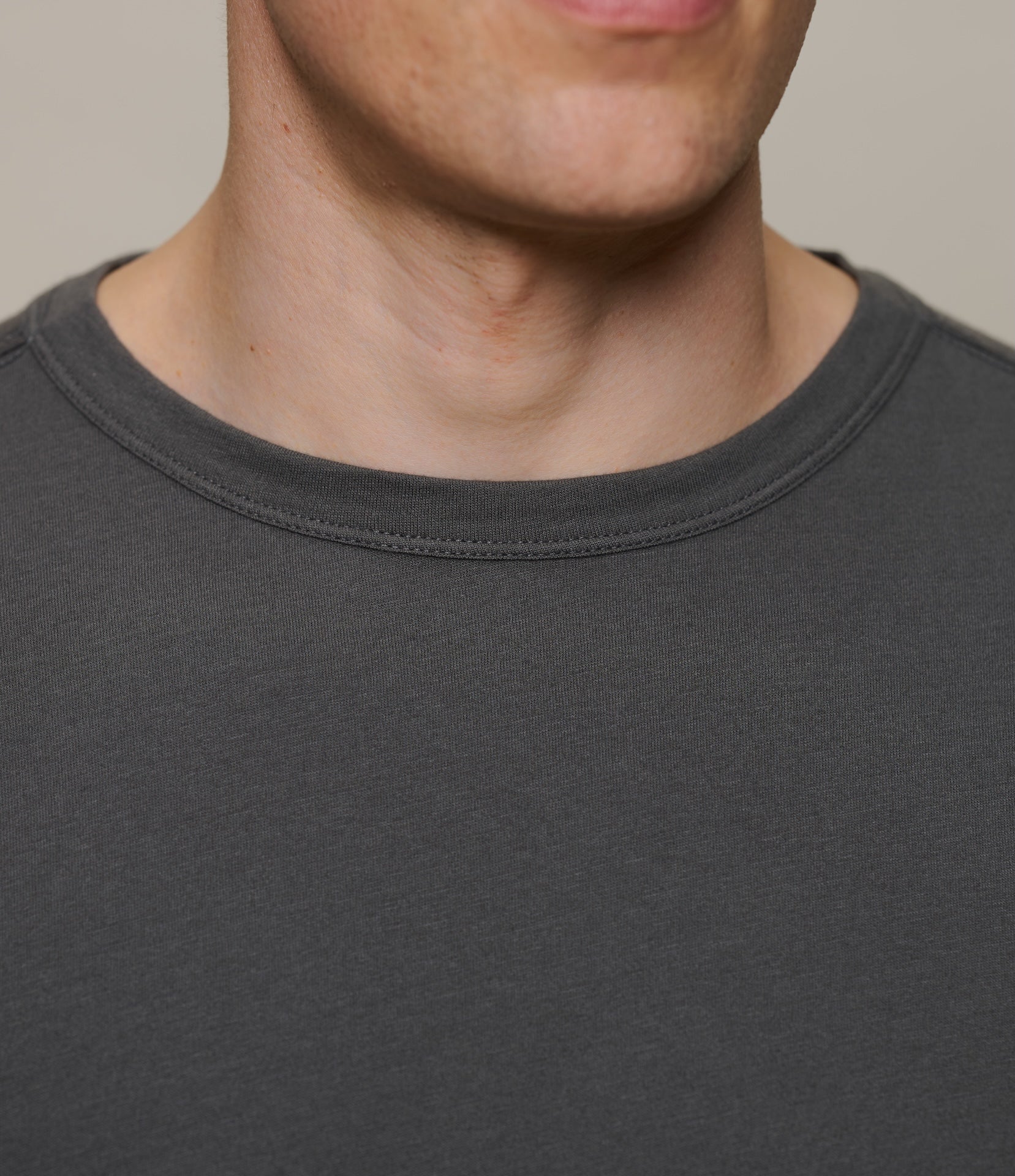 Close-up of a person wearing a dark gray t-shirt against a neutral background