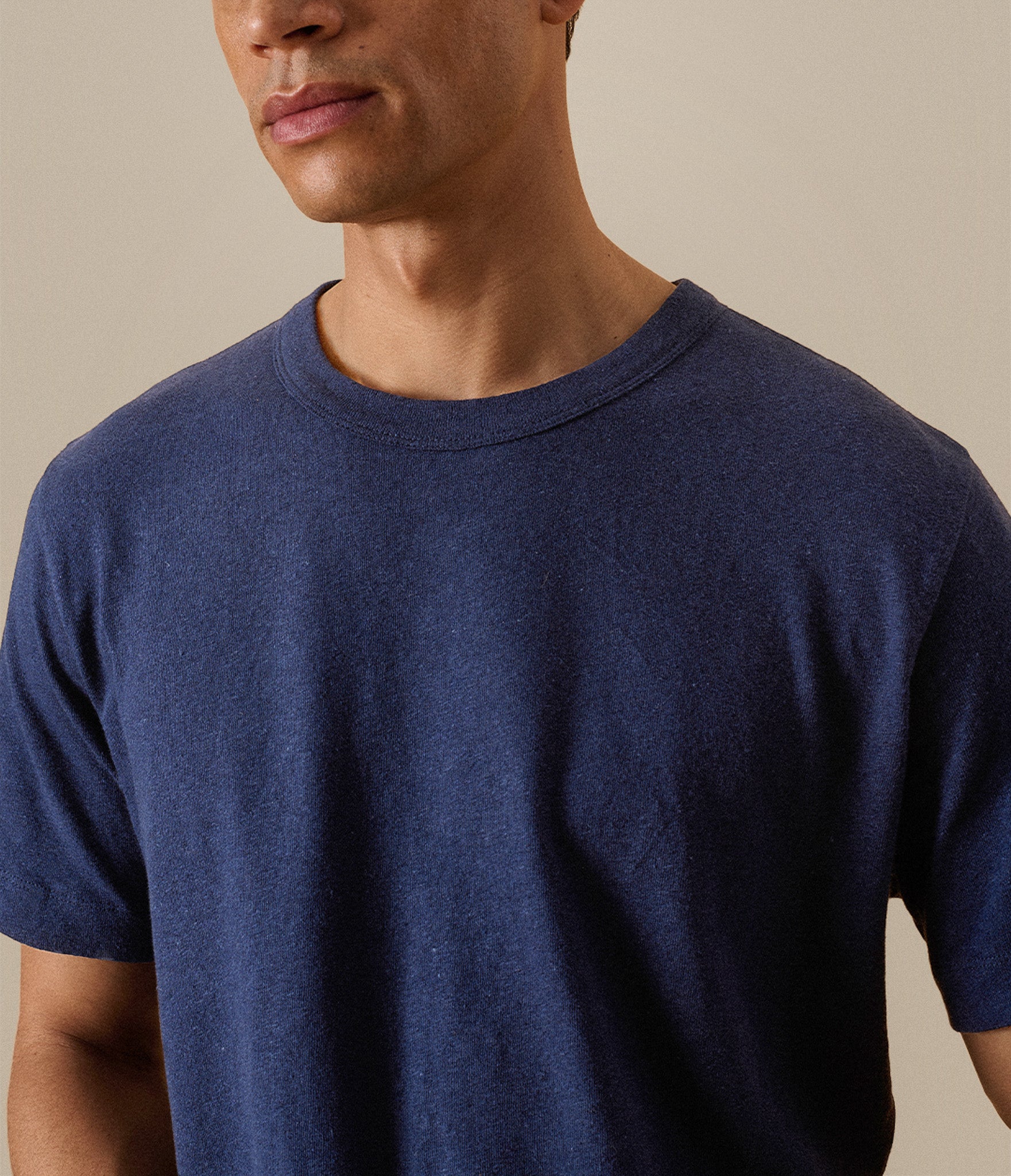 Man wearing a navy blue t-shirt against a beige background