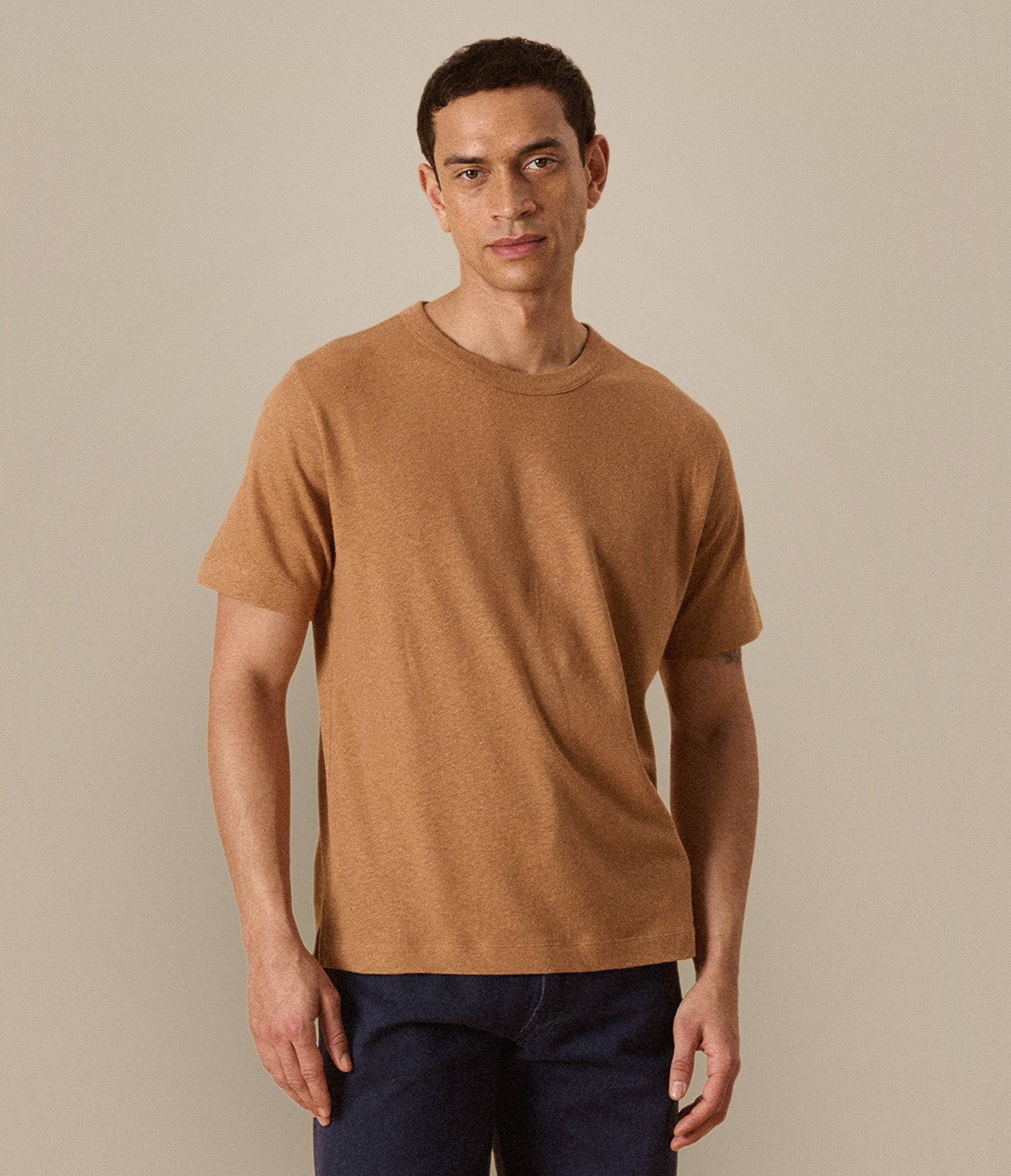 Man wearing a brown linen/cotton t-shirt against a beige background