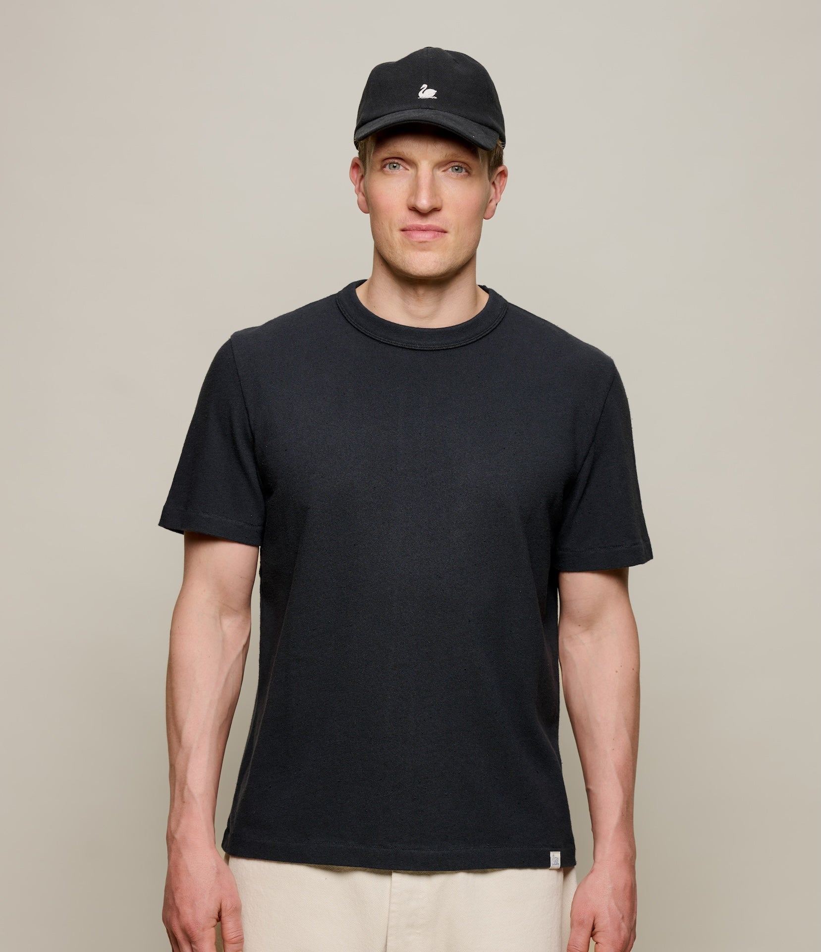 Man wearing a black authentic jersey t-shirt and cap against a plain background
