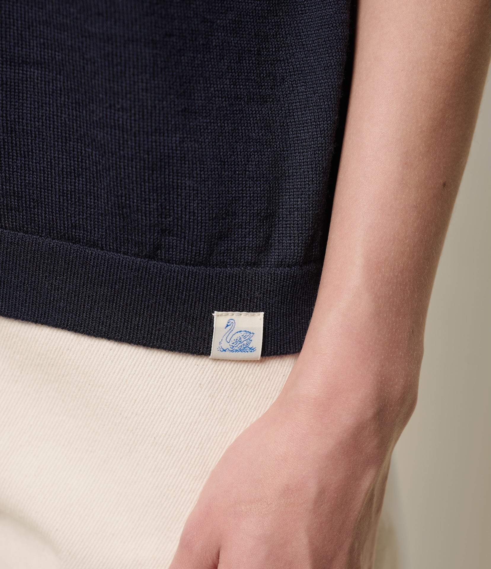 Close-up of a navy knitted polo-shirt with a Merz b. Schwanen label.