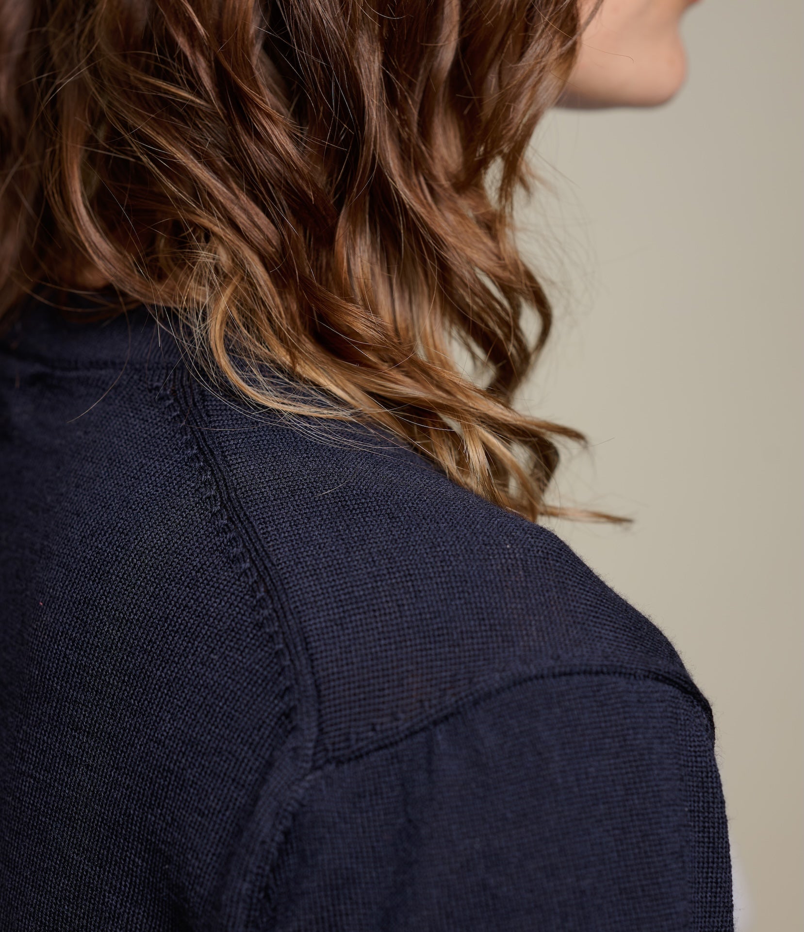 Close-up of a person wearing a dark blue knitted T-shirt with a neutral background