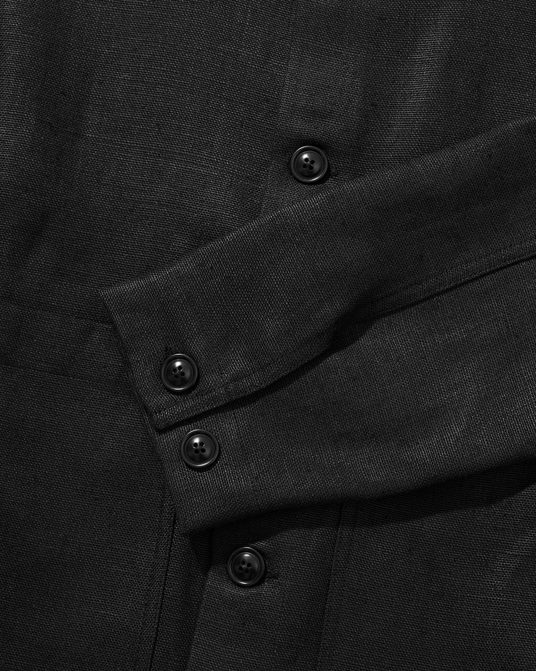 Close-up of a black linen jacket with buttons on a dark background