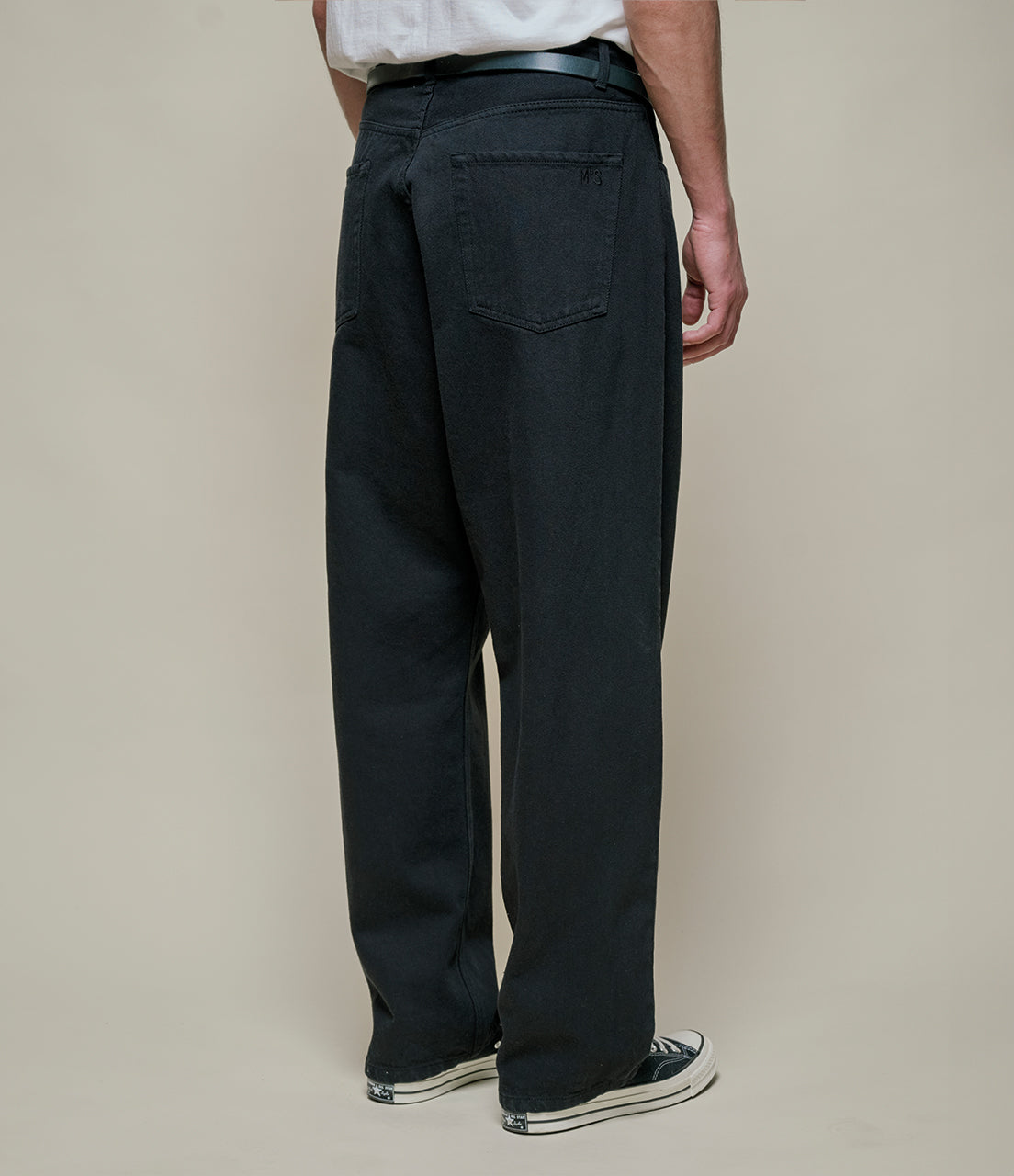 Person wearing black pants on a beige background