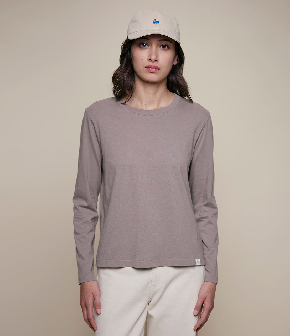 Person wearing a long-sleeve shirt and cap on a plain background