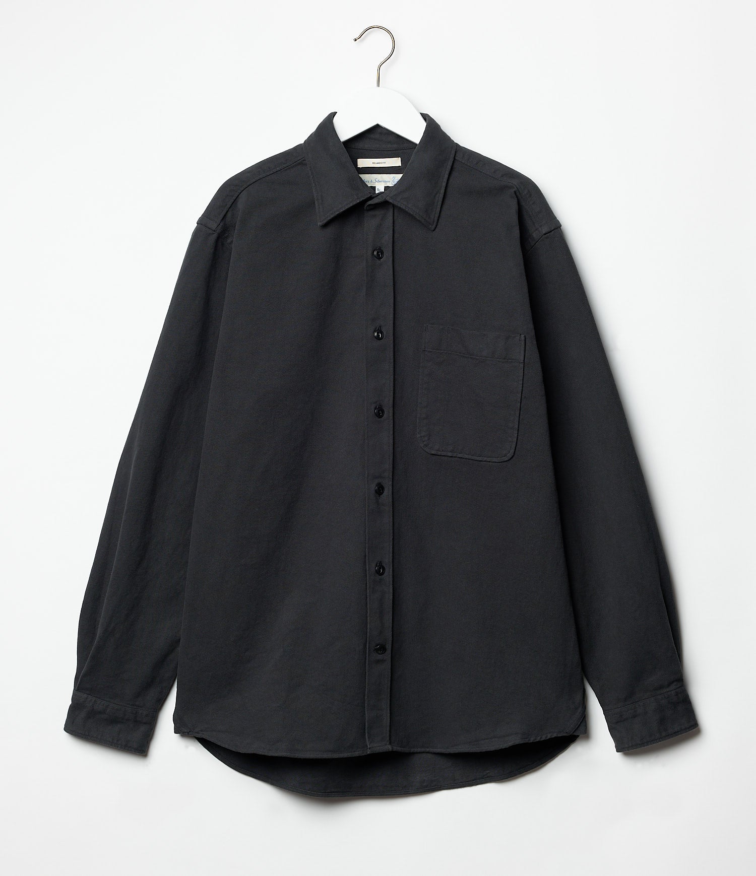 Black twill shirt on a hanger against a white background