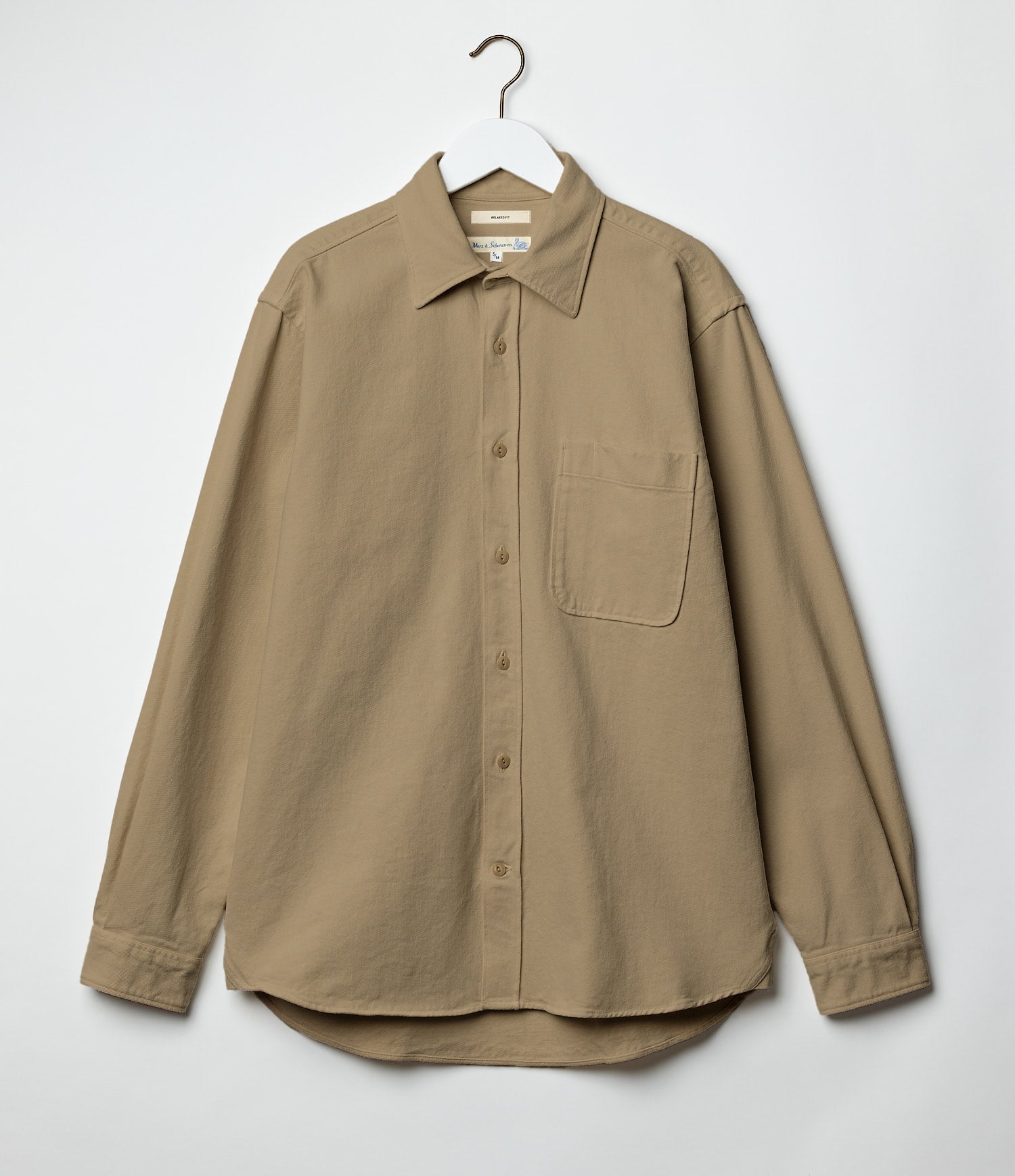 Beige twill shirt on a hanger against a white background