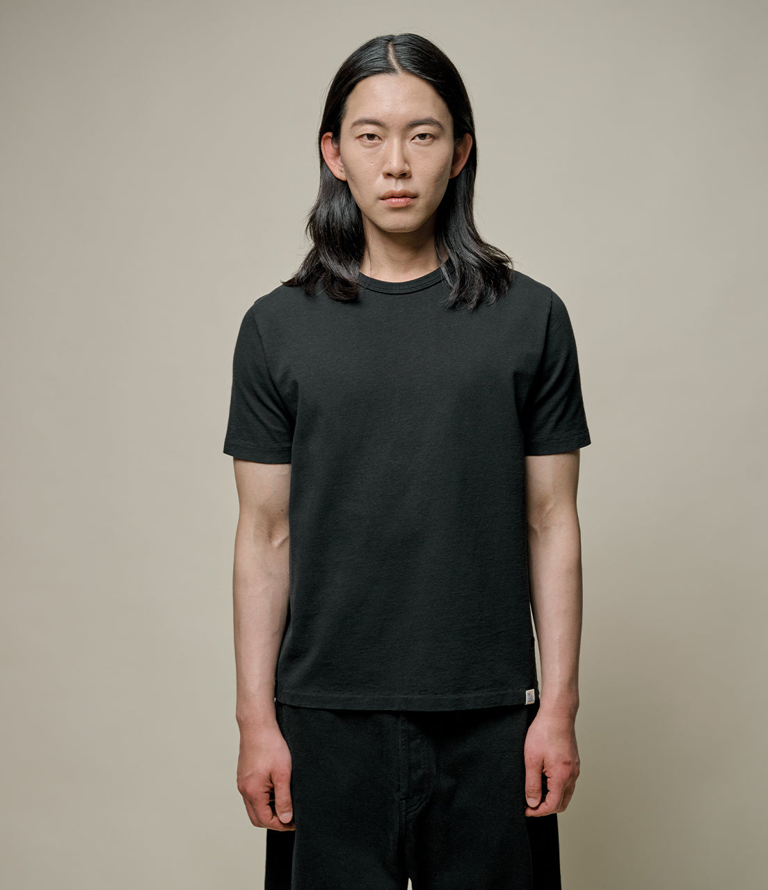 Person wearing a plain black t-shirt against a neutral background