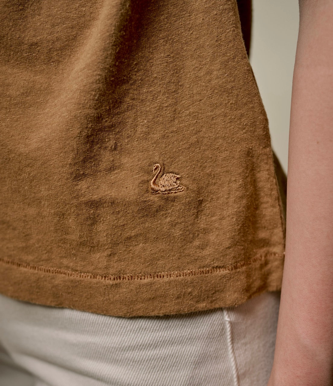 Close-up of brown hemp-cotton fabric with swan embroidery