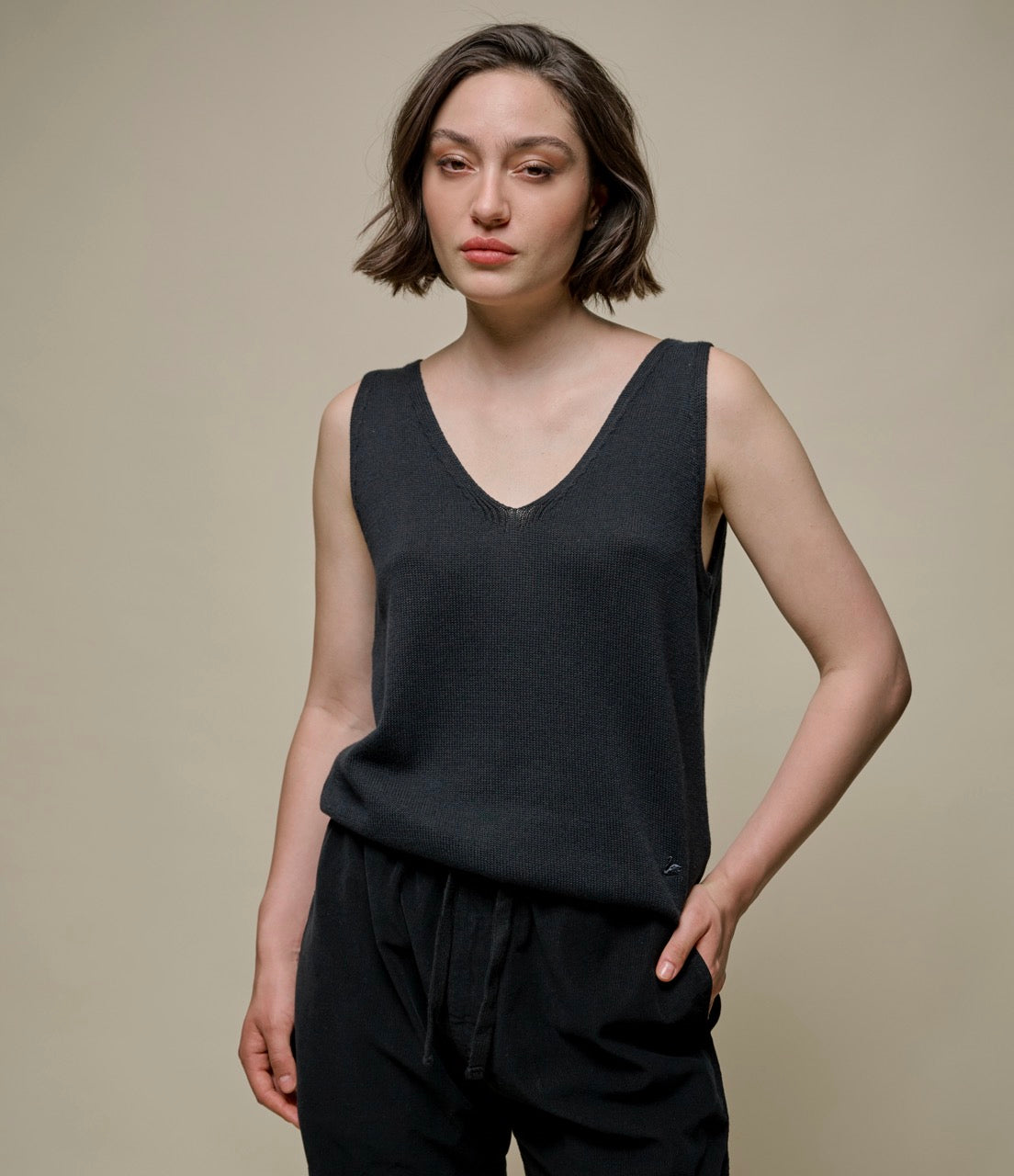 A person wearing a black knitted top with a V-neckline and sleeveless design.