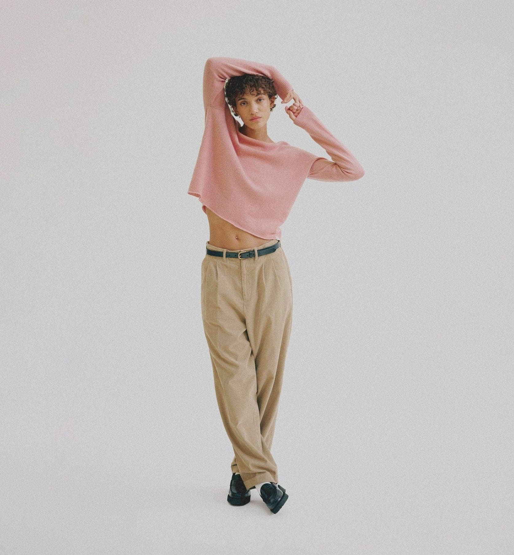Person wearing a pink top and beige pants on a plain background