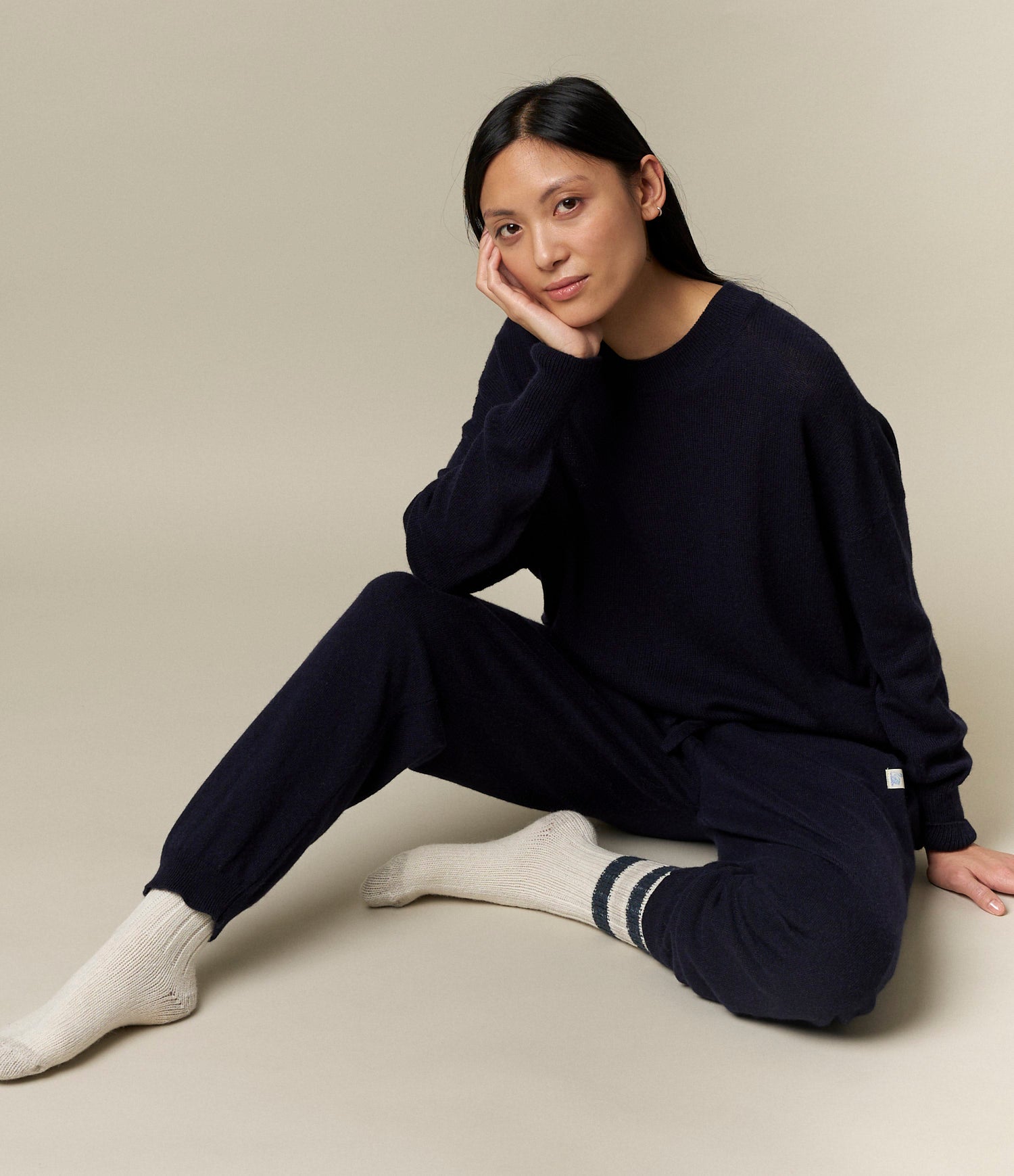 A person sitting on the floor wearing black drawstring pants and white socks.
