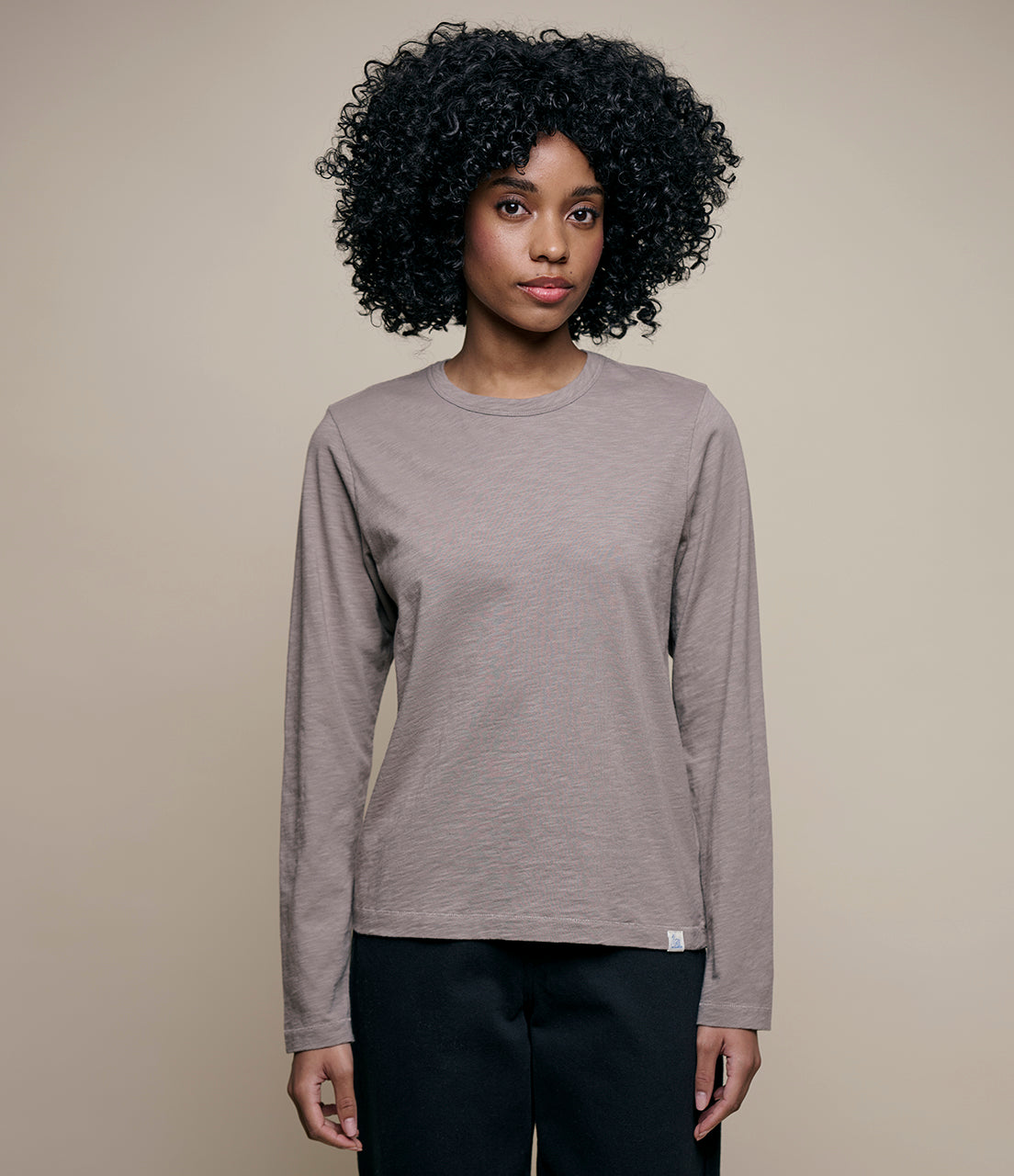 Woman wearing a gray long-sleeve shirt against a beige background