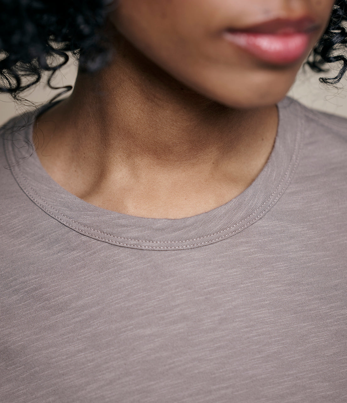 Close-up of a person wearing a gray shirt with a blurred background